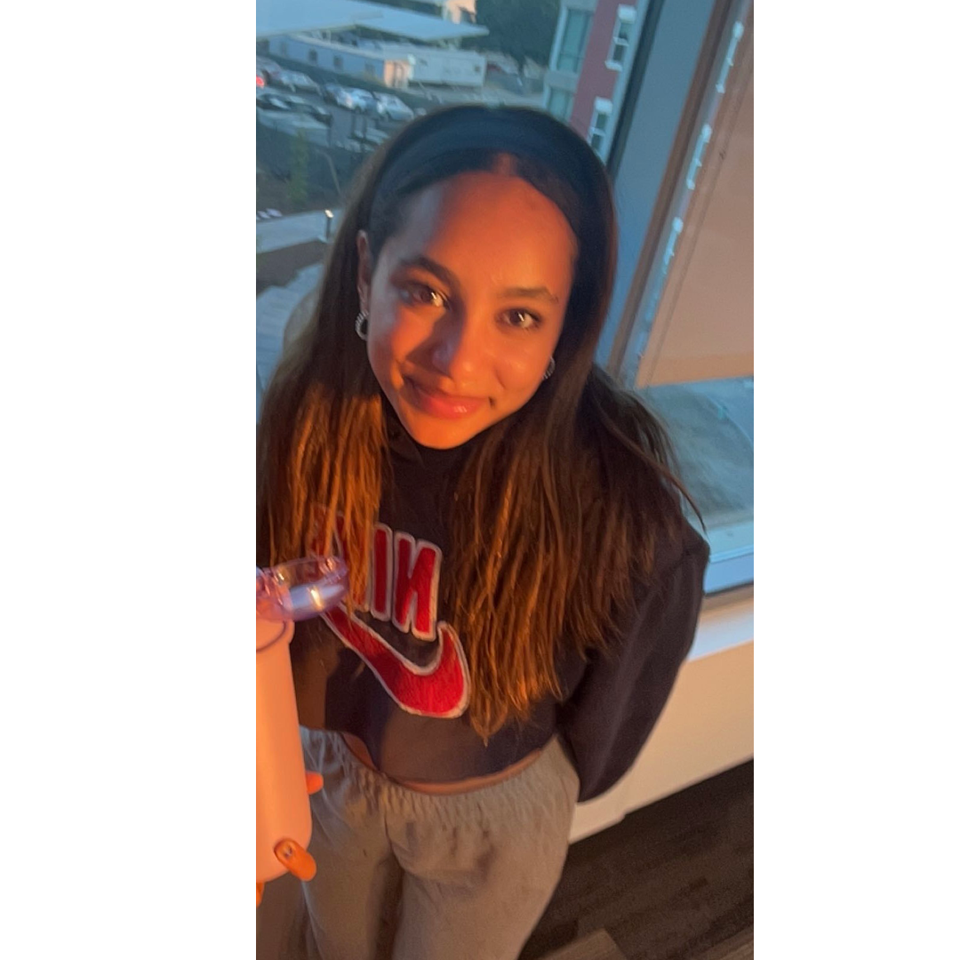Portrait of Student Health Peer, Christiani Marte, in front of a window at the JC campus.